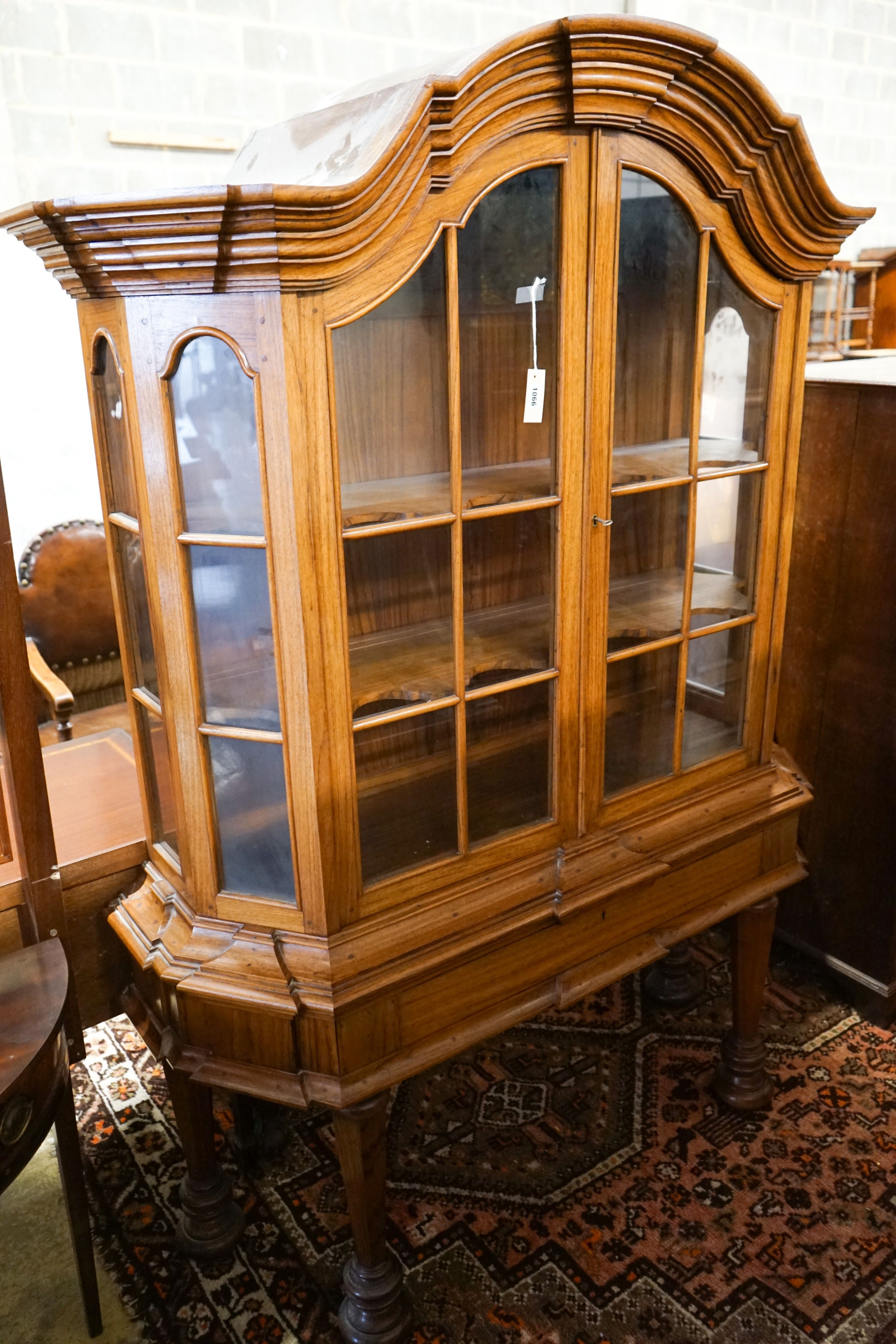 An 18th century style Dutch walnut display case, with double-arched moulded cornice over a pair of astragal-glazed panelled doors, frieze drawer and base with octagonal tapered legs and lion feet, length 132cm, depth 46c